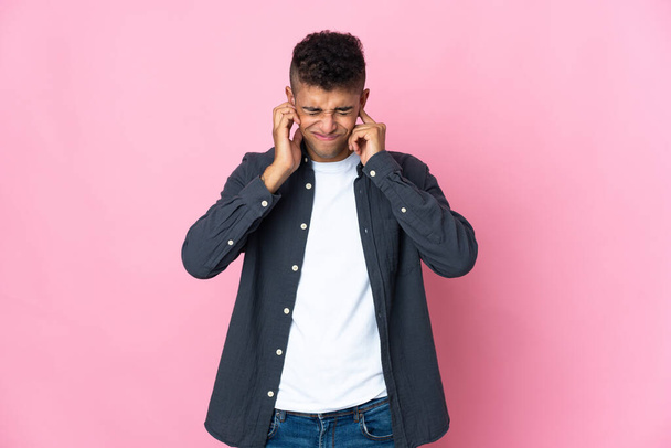 Young Brazilian man isolated on pink background frustrated and covering ears - Foto, Imagem