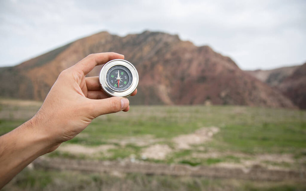 holding a compass on the background of a reddish mountain - Photo, Image