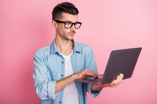 Foto del hombre de negocios guapo enfocado mantenga el trabajo del ordenador portátil aislado sobre fondo de color rosa pastel - Foto, imagen