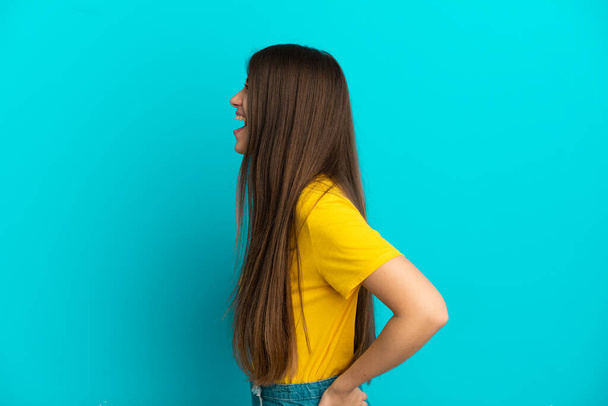Young caucasian woman isolated on blue background laughing in lateral position - Фото, зображення