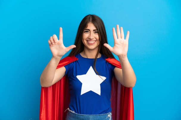 Super Hero valkoihoinen nainen eristetty sinisellä taustalla laskenta seitsemän sormilla - Valokuva, kuva