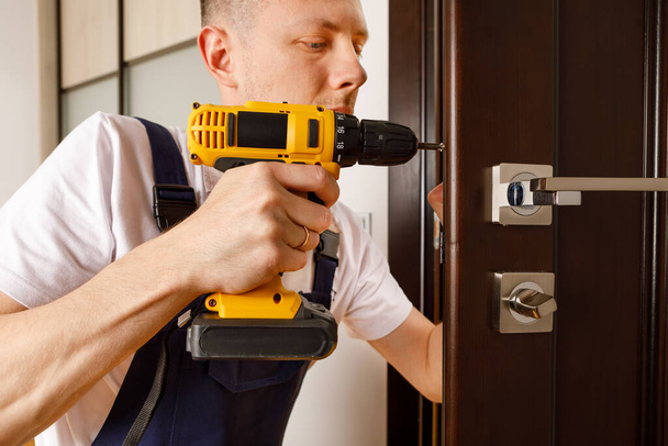 a man repairing a doorknob. Handyman repair the door lock in the room - Zdjęcie, obraz