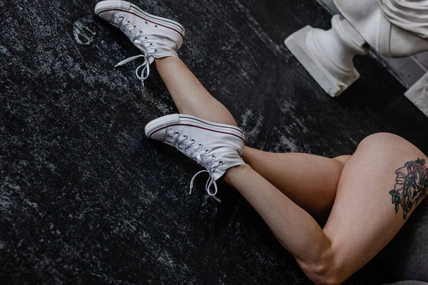 Cropped image of female legs wearing white sneakers - Fotó, kép