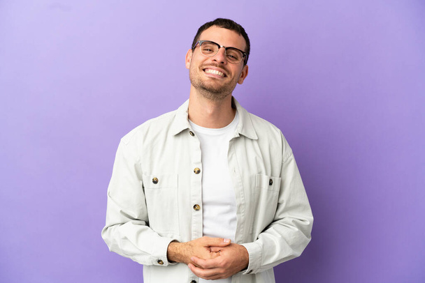 Brazilian man over isolated purple background laughing - Foto, afbeelding