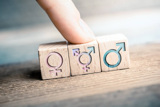 Γυναίκα, τρανσέξουαλ και αρσενικά εικονίδια σε 3 μπλοκ Wodden με ένα δάχτυλο στην ΛΟΑΤ σημάδι - Φωτογραφία, εικόνα