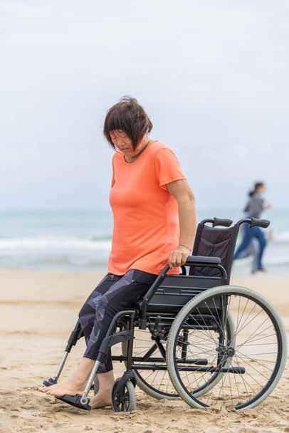 Mujer asiática levantándose de la silla de ruedas para hacer ejercicios de recuperación después de infectarse con covid-19 - Foto, imagen
