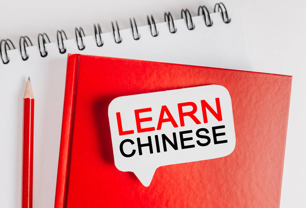 Texto Aprende chino en una pegatina blanca con papel de oficina de fondo. Flat lay sobre el concepto de negocio, finanzas y desarrollo - Foto, Imagen