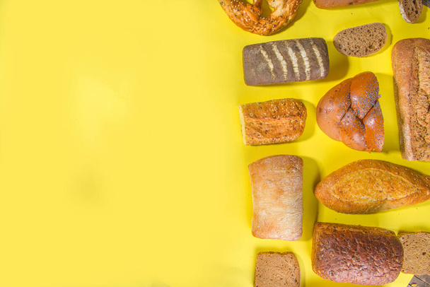 Ассортимент различных вкусный свежеиспеченный хлеб, на модном ярком фоне вид сверху копия пространства, шаблон на желтый - Фото, изображение