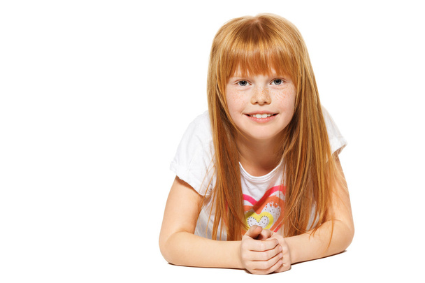 Veselá holčička s červenými vlasy, který lže. izolované na bílém pozadí - Fotografie, Obrázek