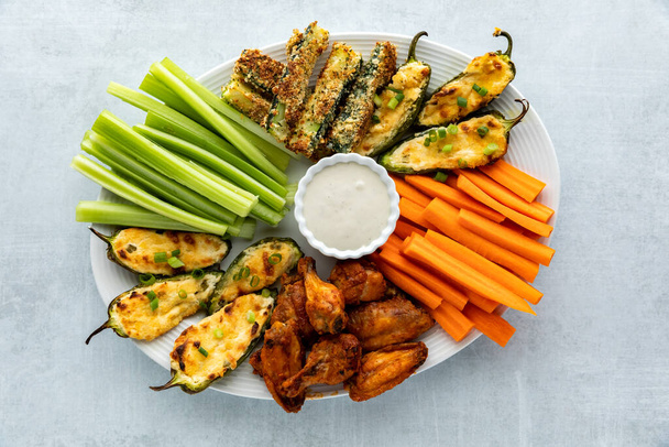 Top down view of an appetizer platter filled with homemade baked appetizers and crispy cold celery and carrots sticks. - Photo, Image