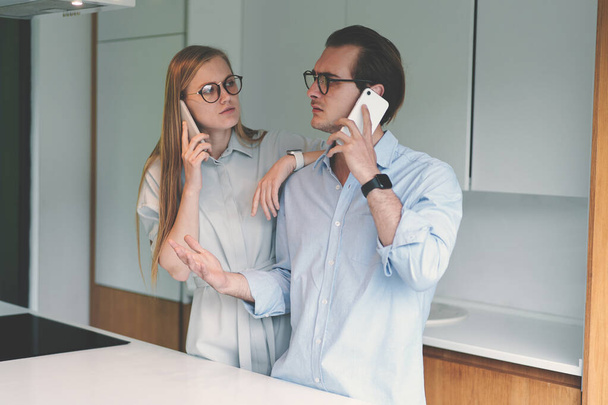 Otthonról dolgozó és telefonon beszélő fiatal házaspár - Fotó, kép