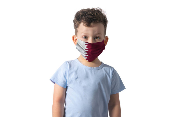 Atemschutzmaske mit Flagge von Katar Weißer Junge setzt medizinische Gesichtsmaske isoliert auf weißem Hintergrund auf. - Foto, Bild