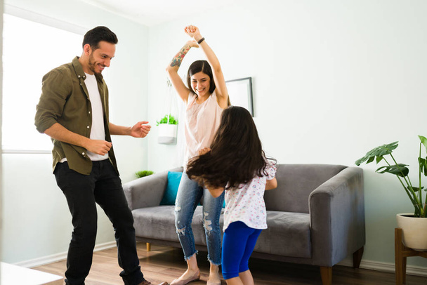 Faire de bons souvenirs de famille. Parents ludiques riant et dansant avec leur petit enfant dans le salon  - Photo, image