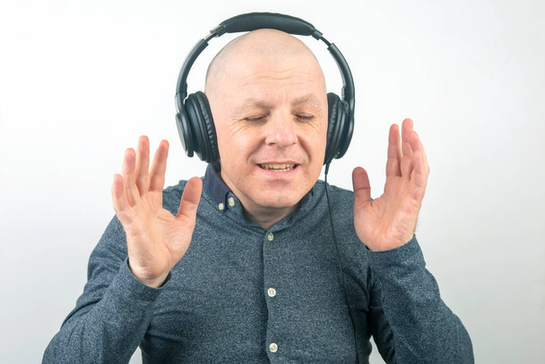 άνθρωπος με κλειστά μάτια ακούει μουσική με ακουστικά σε ελαφρύ φόντο - Φωτογραφία, εικόνα