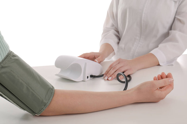 Doctor checking blood pressure of woman at table on white background, closeup - Photo, image
