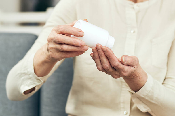 Ręce starszej kobiety, na którą wylewa tabletki przepisane przez lekarza. Koncepcja zapobiegania chorobom i ich leczenia - Zdjęcie, obraz