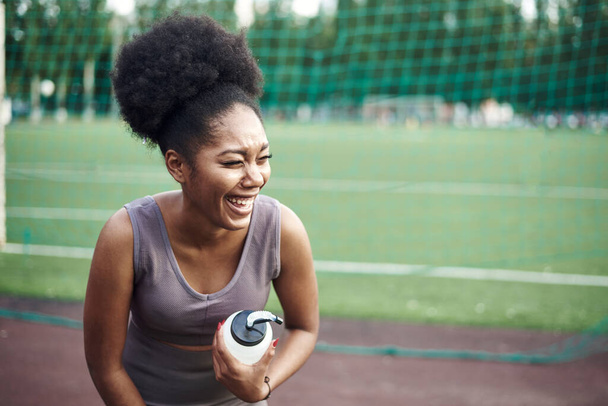 スポーツの制服を着た陽気な黒人女性が笑います。ライフスタイル、アウトドアスポーツ - 写真・画像
