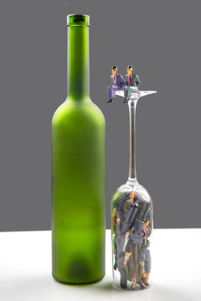Мініатюрні люди. різні люди алкоголіки на дні келиха вина. концепція проблеми алкоголізму в суспільстві
 - Фото, зображення