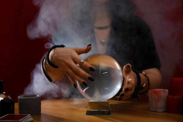 Soothsayer using crystal ball to predict future at table indoors, closeup - Foto, imagen
