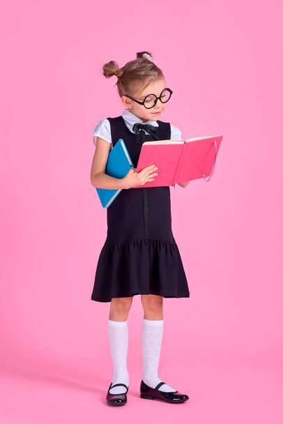 Cute little girl with glasses and books on pink background, spac - Photo, image