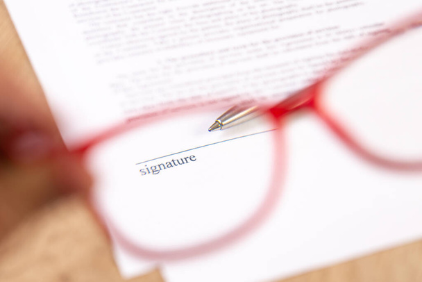 Óculos na mão e caneta esferográfica para a assinatura do Contrato. - Foto, Imagem