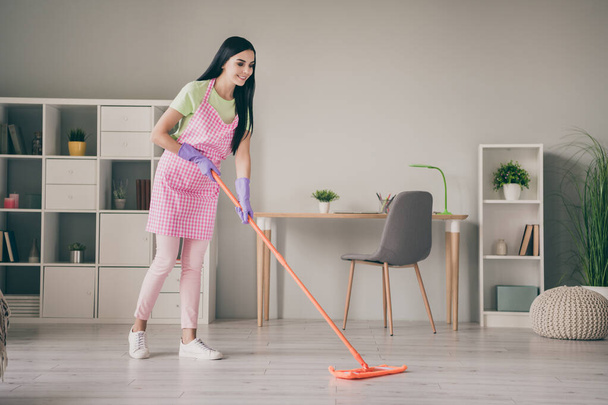 Full length body size view of lovely cheerful long-haired girl wiping floor doing cleanup service at light interior room - Foto, afbeelding
