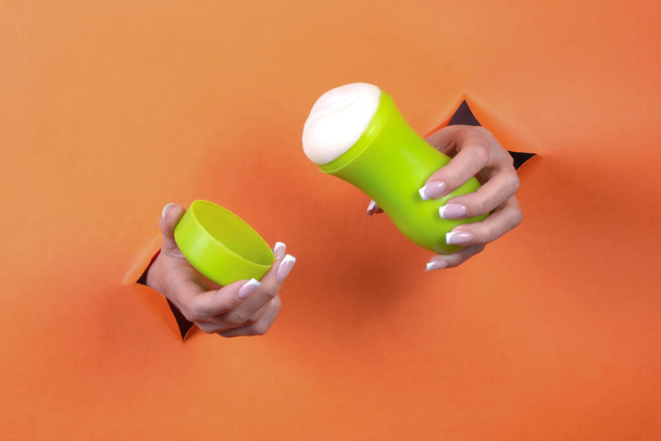 Adult sex toys in women's hands on an orange background. - Фото, изображение