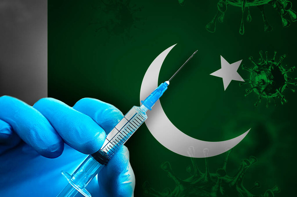 Campaña de Vacunación Covid-19 de Pakistán. Una mano en un guante de goma azul sostiene una jeringa con la vacuna contra el virus covid-19 frente a la bandera de Pakistán. Concepto de vacunación contra el Coronavirus - Foto, Imagen