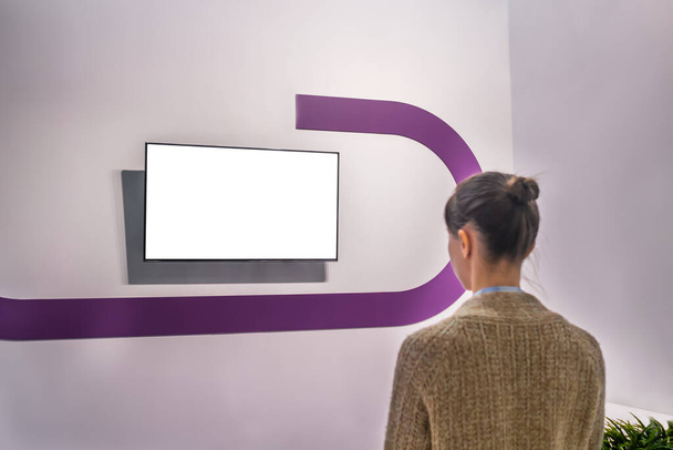 Mujer mirando la pared de exhibición blanca en blanco en exposición - concepto de pantalla blanca - Foto, Imagen