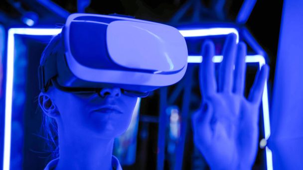 Mujer joven usando auriculares de realidad virtual en la exposición interactiva oscura VR - Foto, imagen