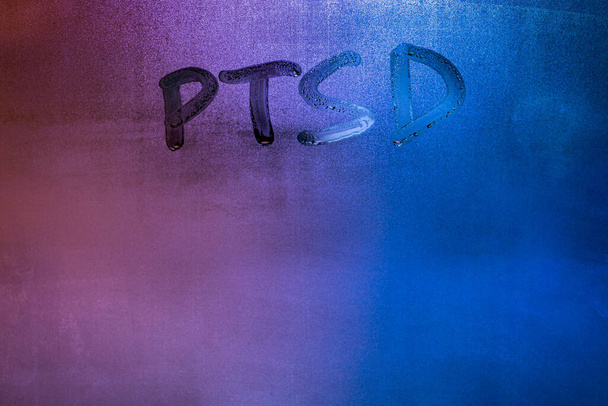 аббревиатура ptsd - посттравматическое стрессовое расстройство - от руки написано на ночном мокром стекле - Фото, изображение