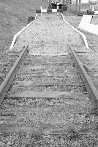 Мертвий кінець залізниці закінчується курганом і знаками, що забороняють рух транспорту. Чорно-біле зображення
. - Фото, зображення