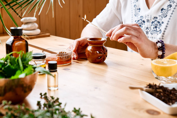 Woman prepares aromatherapy session at the table with essential oil diffuser medical herbs, different types of oils and essences. Aromatherapy and alternative medicine concept. Natural remedies. - Fotó, kép