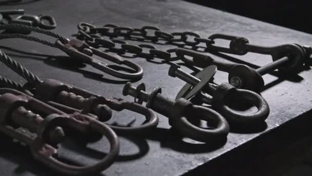 Zbliżenie kute łańcuchy żelaza i inne elementy leżące na stole w warsztacie spawalniczym fabryki ciągników w pomieszczeniach - Materiał filmowy, wideo
