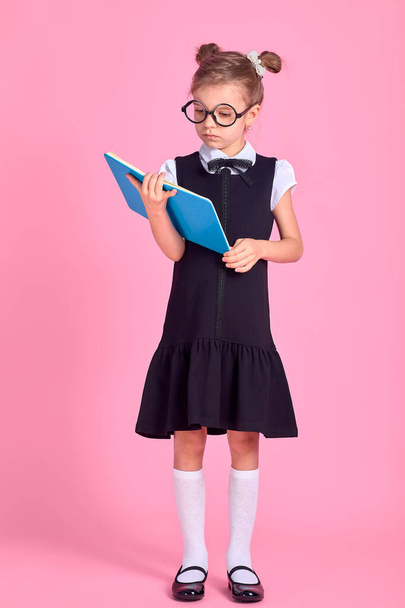 Cute little girl with glasses and books on pink background, spac - Valokuva, kuva