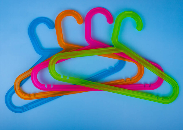 Colored plastic hangers on blue background. Storage and sales concept - Фото, изображение