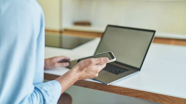 Lähikuva näkymä liikemies työskentelee kotoa kannettavan tietokoneen ja älypuhelimen - Valokuva, kuva