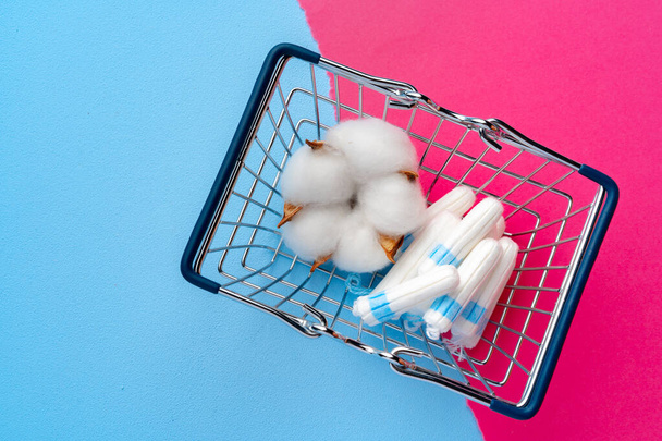 Shopping cart with medical tampons on pink and blue background - Photo, image