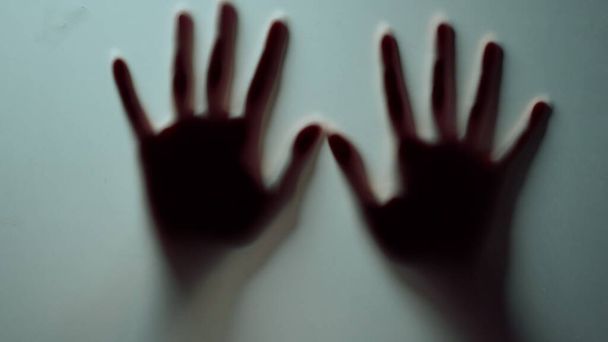 Макро две женские руки прижимаются к стеклянной стене в помещении.. - Фото, изображение