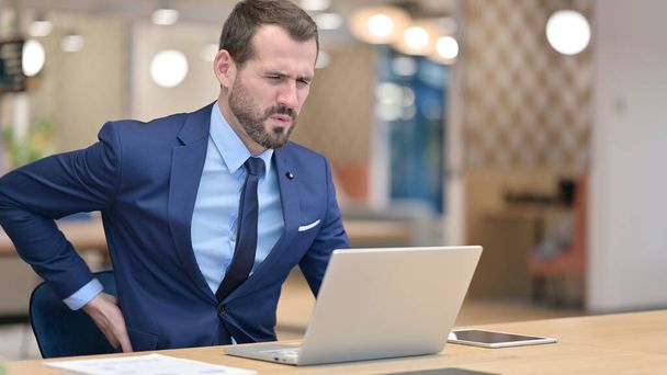 Tired Middle Aged Businessman with Laptop having Back Pain in Office  - Photo, Image