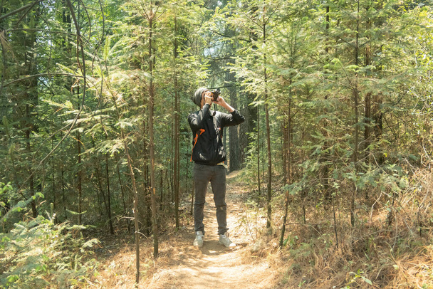 A man taking pictures with a professional camera inside a forest - Φωτογραφία, εικόνα