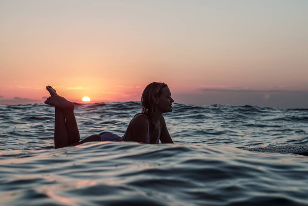 Portrait from the water of surfer girl with beautiful body on surfboard in the ocean at sunset time in Bali - Fotoğraf, Görsel