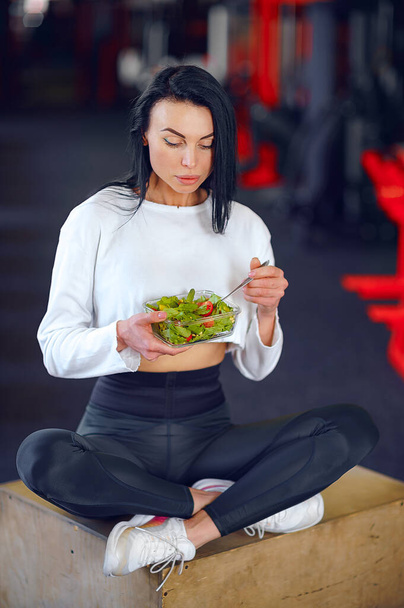 спортивна жінка їсть салат
 - Фото, зображення