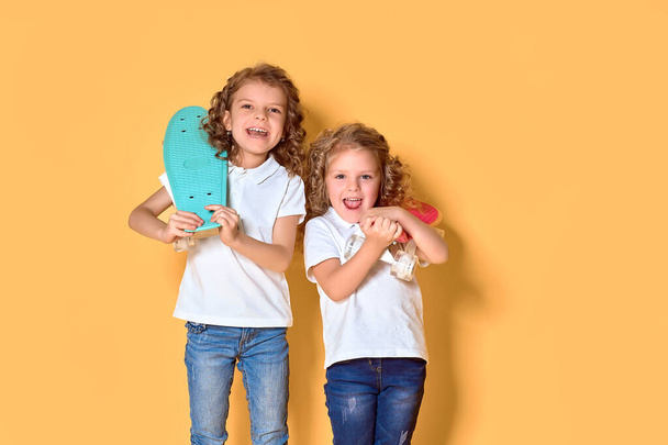 Two Active and happy girls with curly hair having fun with penny - Фото, изображение