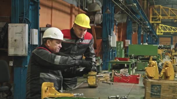 Maschio medio di impiantisti maschi che assemblano macchinari per trattori con chiave inglese - Filmati, video