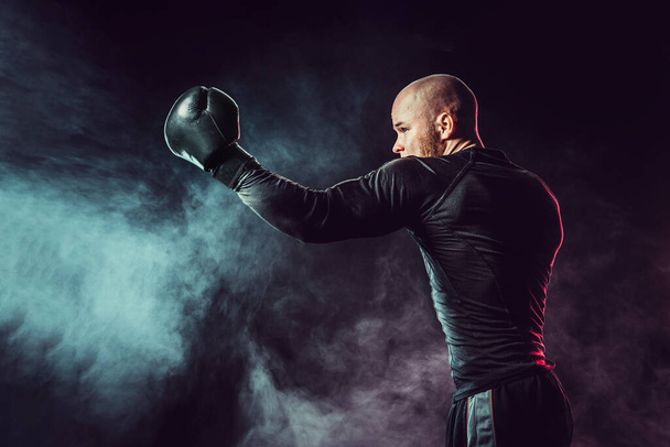 Sportsman boxer fighting, hitting uppercut on black background w - Zdjęcie, obraz