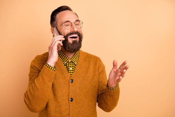 Photo of positive cheerful mature man call smartphone say joke laugh wear sweater isolated over pastel color background - Фото, изображение