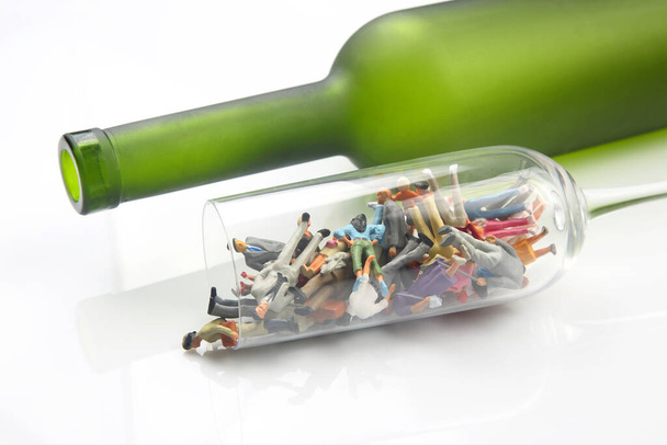 miniaturní lidé. koncepce problému závislosti na alkoholu. alkoholici jsou ve sklenici vína na pozadí láhve. - Fotografie, Obrázek