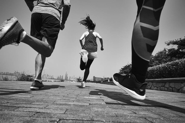屋外でジョギングをしている3人の若いアジアの大人,リアとローアングルビュー,黒と白 - 写真・画像