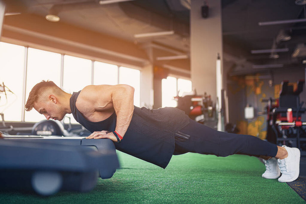 Young athletic man doing push-ups in gym. Muscular and strong gu - Foto, Imagem